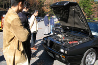 「シャマル」のV8ツインターボエンジンを覗き込む参加者たち。赤い結晶塗装のヘッドを前に、話しているのはやはりあのこと？