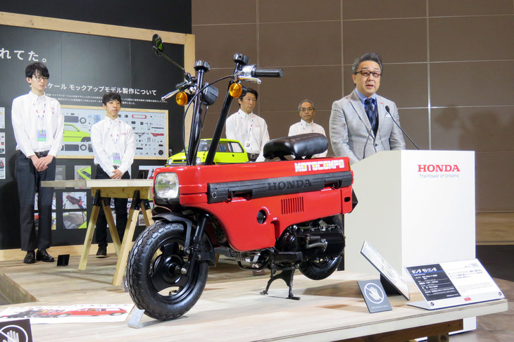 「ホンダ・モトコンポ」と本田技研工業の朝日嘉徳氏。奥に立っているのは、4分の1のスケールモデルを製作したメンバー。