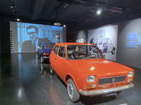 「フィアット127」。後方スクリーンにはデザイナー、ピオ・マンズー氏の姿が。2021年、トリノ自動車博物館の企画展で。