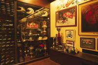 2階のコレクションルームに展示されているムナーリをはじめとするラリードライバーのヘルメットや彼らが手にしたトロフィーなどの記念品の数々。左に見えるのは1/43スケールのミニチュアカーのケース。ミニチュアカーはものすごい台数で、かなりの数を原田さんがキットを組んだもの。もう増やせないらしい。