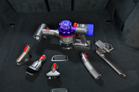 「Dyson V7 Car＋Boat」と付属のアタッチメント。写真上が「ミニ モーターヘッド」を装着した本体で、時計回りに「カーチャージャー」「隙間ノズル」「延長ホース」「ハードブラシ」「コンビネーションノズル」「ミニ ソフトブラシ」が並ぶ。