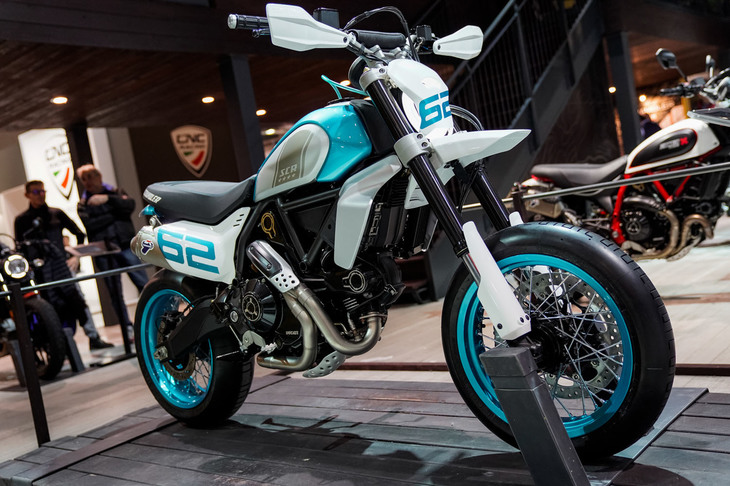 この「スクランブラー モタード」は、EICMAでドゥカティが発表する2度目のコンセプトモデル。排気量800ccの空冷L型2気筒エンジン搭載のオフロードスポーツモデル「スクランブラー デザートスレッド」をベースに、前後17インチホイール＋スポーツタイヤの“スーパーモタード”スタイルをつくり上げた。