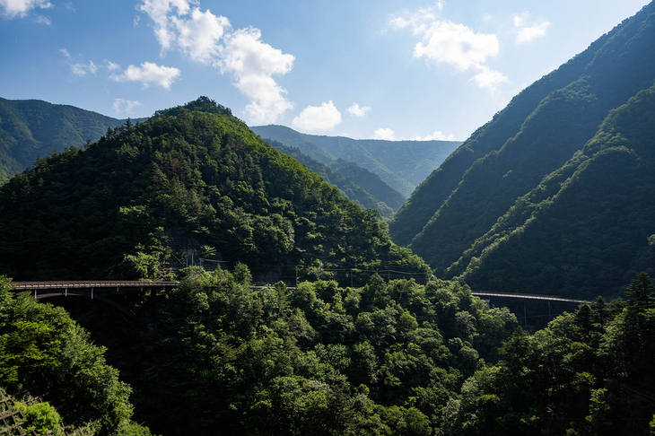 ダムにかかった橋から市街地方面を見る。山々の隙間に国道139号が見えている。