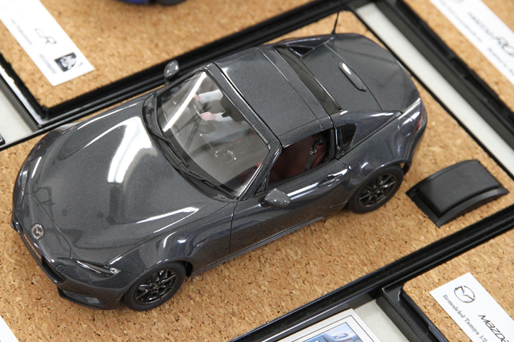 同じ作者による「マツダ・ロードスターRF」。いつの間にRFのキットが発売されていたのだろうと思いきや、タミヤ製1/24「ロードスター（ND）」を改造したもの。キットが存在するとしか思えない見事な出来栄えだが、驚くのはまだ早い。その秘密は、展示台の右下方に見える黒い横長の出っ張り部分にある。