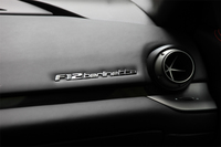 
	写真は、ダッシュボードの助手席側に配されるロゴバッジ。その横に見えるエアコン吹き出し口は、ボールジョイント的な動きで、自由に風向を変えられる。
	