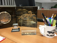 卓上には、スバル・イタリアから授けられた盾やノベルティーが。マグカップに描かれた2代目の“丸目仕様”「レオーネ」が懐かしい。