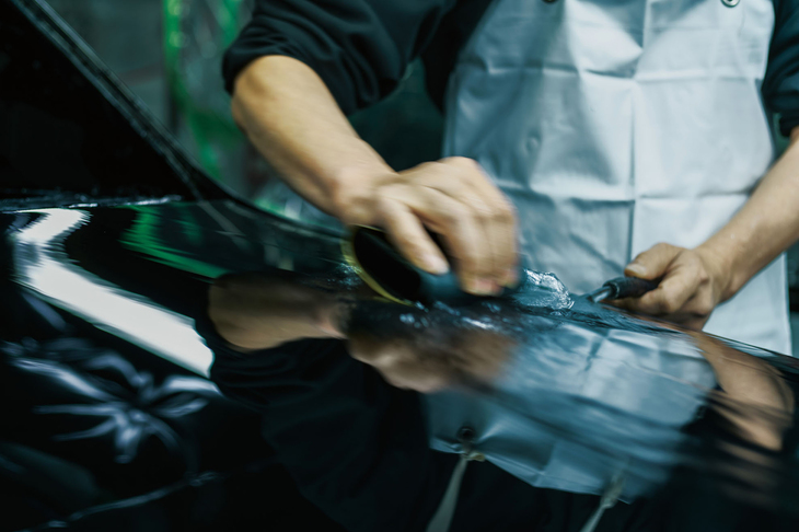 漆黒のボディーカラーは、7層の塗装に研ぎと磨きの作業を加えて仕立てられる。写真は水研ぎの様子。