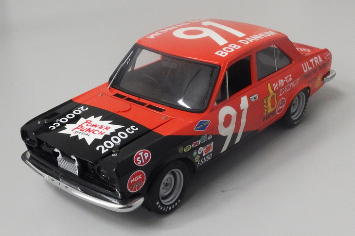 テレビドラマ『特別機動捜査隊』の覆面パトカー仕様としてリリースされた、往年の三共製1/24「日産セドリック」（型式名130こと2代目）をベースにしたストックカー。都内でスピードショップを営んでいたこともあるアメリカ人レーシングドライバーのロバート・ダンハムが、1968年の日本カンナムに併催された全日本ストックカー富士200kmで駆った仕様がモデル。特注インレタによる、リアドアに描かれた「ハイ・パホーマンス エンジニアリング」にシビれる。