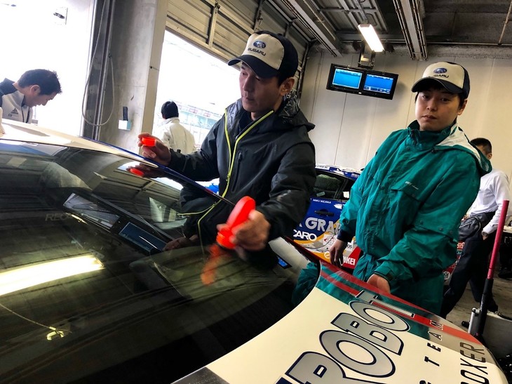 走行前に窓ガラスの撥水（はっすい）コーティングをしてくれている様子です。今大会は天気を読むことが難しく、雨が降ったりやんだり、前のマシンがはっきりと見えないようなとても濃い霧の中を走ったり、ということもありました。私はBRZに乗り始めてから、ハーフウエットの路面で走ったことはありましたが、雨が多く降り続いている中での走行は今回が初めて。オートポリスのコースも初とあって、少し緊張していました。