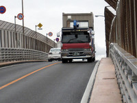 浦戸大橋で。狭い歩道だけにすがって進む歩行者のすぐ傍らを、ダンプがごう音を立てて駆け下りてくる。強風にあおられると本当に怖い。