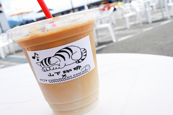 “ごめん寝”スタイルの猫のイラストがかわいらしい、山下珈琲も出店していたので、ハンバーグサンドとともにカフェオレで一服する。山下珈琲は富士スピードウェイと同じ静岡県小山町のコーヒー店で、この日は「ボウタイ＋ブレンド」なるオリジナルブレンドのコーヒー豆も販売していた。