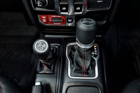 「ラングラー ルビコン」のシフトレバー（右）と駆動切り替えレバー（左）。写真奥の赤いパネル内に、前後ディファレンシャルをロックする「トゥルロック」スイッチが配置される。これを押すだけで前後または後ろのみをロックでき、前後ロック時にはトルクを4輪に均等分配する。