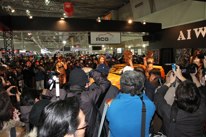 毎回、露出度の高い衣装をまとったコンパニオン目当てにカメコ（カメラ小僧）が殺到することで有名な、カスタム用ペイントのエキスパートであるAIWAのブース。開催初日の朝一番のショーでも、この盛況ぶり。