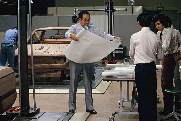 「スカイライン」の開発者として名高い桜井眞一郎氏が、1981年に登場した6代目R30を開発中、という設定のカット。後方に見えるのが製作中の1分の1のクレイモデルで、それを載せているのが定盤である。