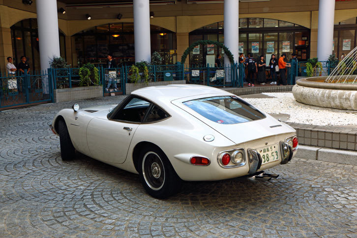 ヒストリーガレージ前の広場にて、来場者の注目を集めながら、噴水のまわりをくるりと回る「トヨタ2000GT」。