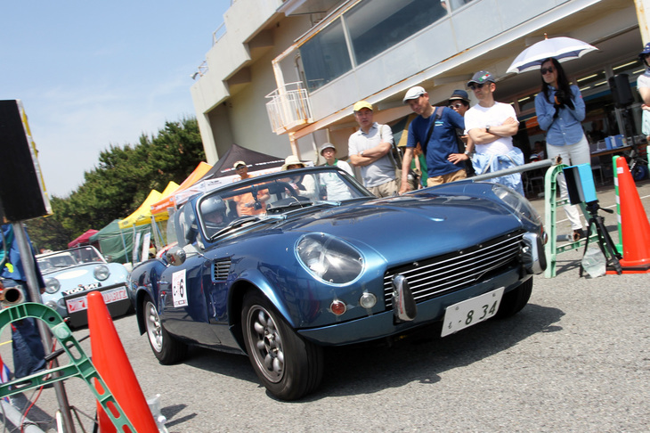 1800cc以下のノーマル車両および1300cc以下の改造車両によるCクラス（出走10台）で、スタートしていく「トライアンフ・スピットファイアMk3」。ルマンに出走したワークスマシンのレプリカキットを装着しており、ノーマルとは顔つきが異なる。