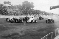 1937年5月に開かれた第3回全日本自動車競争大会における商工大臣杯（国産小型車によるレース）のスタートシーン。先頭集団は戦前にダットサンと覇を競ったオオタのワークスチーム。満員の観衆が座っているのは、今も残るコンクリートのグランドスタンドである。