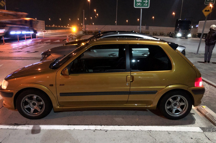 東條氏が用意してくれた「106 S16」には、フランス車専門のチューニングショップJ.ENGINEが手がけた排気システムやセンターマフラー、ビルシュタインのサスペンションなどが組み込まれていた。ボディーカラーは「ブレイズゴールド」と呼ばれる金色で、夜の辰巳PAにもよく似合っている。