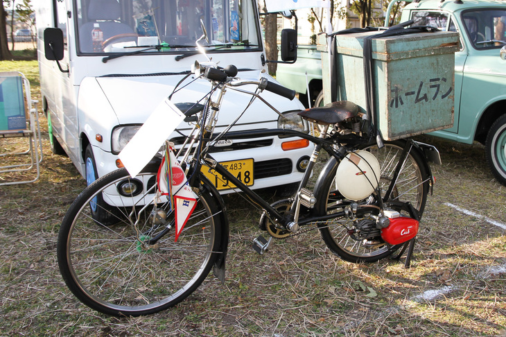 「ホンダ・カブF」。1952年にリリースされた、ホンダの原点となる自転車用補助エンジン。ホーロー製の白い燃料タンクと赤いカバーの付いたエンジンを組み合わせてキット販売された。