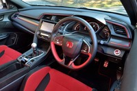 スポーティーさが際立つ室内。下端を水平にカットした「D」シェイプのステアリングが装着されるほか、インパネにはアルマイト調の赤ストライプをあしらったカーボン調パネルが張られる。