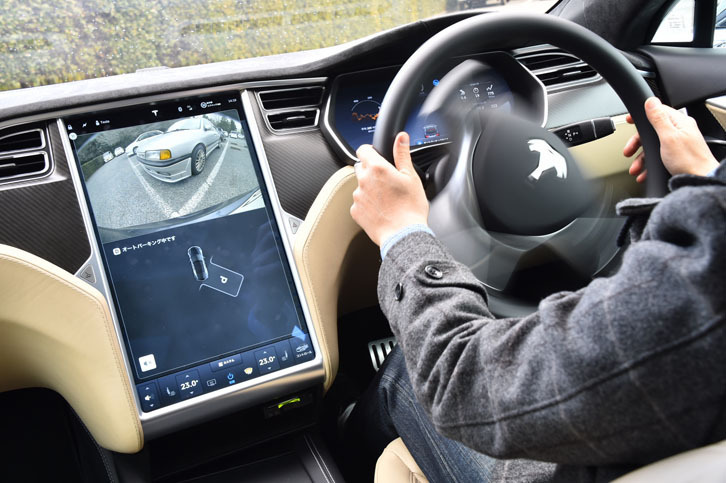 
	オートパーク機能による駐車シーン。「モデルS」は常に自車両の周囲をセンシングしており、空き駐車スペースと思われる空間を認識するとモニターに「P」マークを表示する。そこでドライバーが駐車の意思を伝えると、自動的に駐車操作が行われる。
	