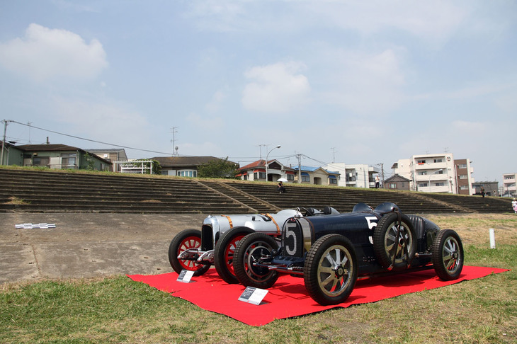 2016年5月、開設80周年記念プレートの除幕式が行われた際の光景。観客席を見上げる位置に、戦前にここで行われたレースに参戦した1926年「ブガッティT35C」（手前）と1924年「カーチス号」が展示された。