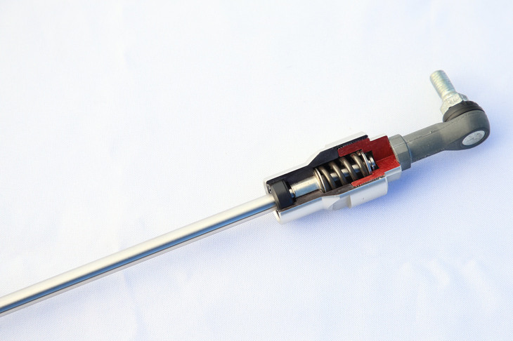 「フレキシブルドロースティフナー」のカット模型。スプリングを仕込んだロッドで車体にテンションをかけ、入力の伝達遅れを解消するパーツだ。