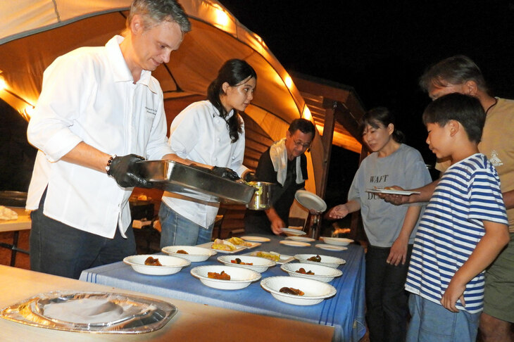 夜もとっぷりと暮れ、いよいよフレンチBBQの時間。セバスチャン・マルタン料理長が、娘さんと一緒に料理を取り分けていく。