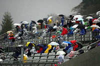 降りしきる冷たい雨の中、視線は、スタートラインに釘付け。レースのスタートを「いまかいまか」と待ちつづけた、1コーナー指定席の観客たち。