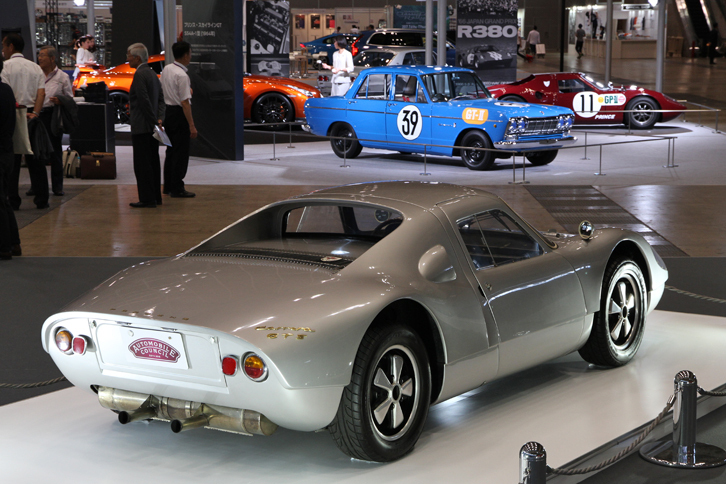1964年の第2回日本グランプリで優勝した「ポルシェ・カレラGTS」（写真手前）と、2位になった「プリンス・スカイラインGT」（奥、レプリカ）。日本レース史に語り継がれる対決を演じた2台が、通路を挟んで主催者コーナーと日産ブースに展示され、対峙（たいじ）していた。この配置は偶然か、それとも意図したものなのか？