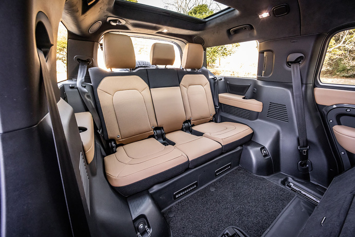 3人掛けとなる「ディフェンダー130」の3列目シート。V8モデルでは、5人乗りと7人乗りシートも選択できる。背もたれは40：20：40の分割可倒式。ヒーター機能とシートの左右にはドリンクホルダーも備わる。