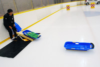 タイヤのトレッド面を貼り付けた、実験用のソリを滑らせる。緑色の袋は重りで、片方を滑らせたら、もう片方に積み替え。同じ条件で試された。