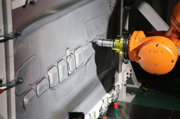 棒状の工具を取り付けられたロボットが、パネルを徐々に変形させて成形する「インクリメンタル成形」技術を応用。ロボットを対向側にも配置して、より複雑な形状の成形を可能にしている。（写真：日産自動車）