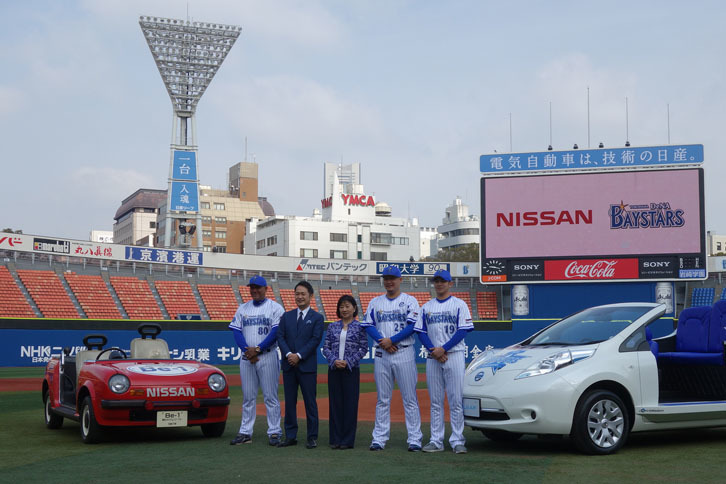 写真左からアレックス・ラミレス監督、DeNAベイスターズの岡村信悟社長、日産の星野朝子専務、筒香嘉智選手、山﨑康晃選手。バックスクリーンの上の看板には「電気自動車は、技術の日産。」、レフト側照明塔の看板には「一台入魂」、写真にはないが、ライト側には「横浜生まれ」と記されている。