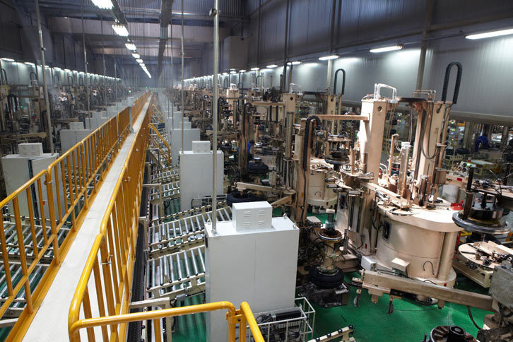 “グリーンタイヤ”を加熱・加圧するとともに、トレッドパターンなどのデザインを施す加硫工程。1日につき200本のタイヤを加硫する加硫機が、8本のラインにそれぞれ19機並べられている。