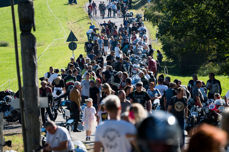 出走を待つライダーたちのピットは、道路脇のフェンス。ライダー同士がノンビリと会話し、観客たちはマシンをじっくりと見て歩く。
