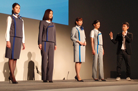 発表会場でのひとこま。デザイナーの江角泰俊氏（写真右端）が自ら、春夏用（右側の2着）と秋冬用（左側の2着）それぞれのポイントを解説した。
    