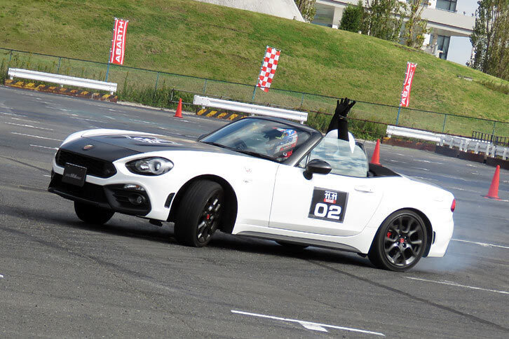 後輪から白煙を吹き上げながら、大胆なドリフトを披露。助手席の同乗者も両手を突き上げて大興奮である。