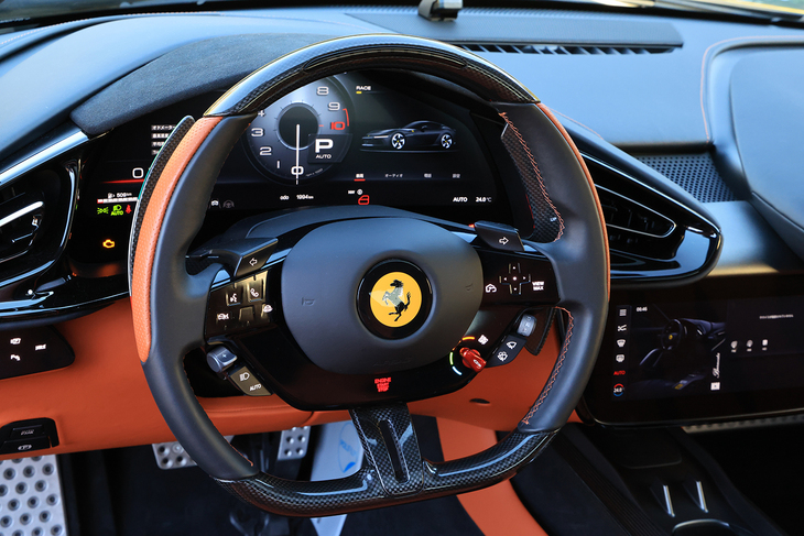 ステアリングリムはカーボン製。スタート／ストップスイッチはホーンパッドの下に備わっており、まずはブレーキを踏まずに押して車両に電気的なチェックを回し、その後にあらためてエンジンをかけるというのが最新フェラーリの始動法である。