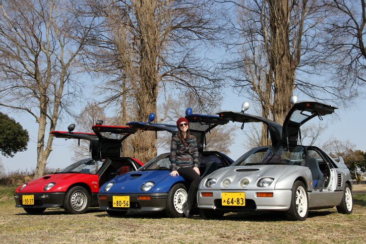 1992年すなわち平成生まれだが、特例により参加した3台の「オートザムAZ-1」。中央の女性は、この青いクルマのオーナーであるカリフォルニア・ガールのアシュリー嬢。彼女はターボチャージャーのトップメーカーであるハネウェル（旧ギャレット）のエンジニアで、今年1月から半年間の予定でハネウェルジャパンに出向中。会社でターボの設計に従事するいっぽう、プライベートでは「コブラ」「マツダRX-7（FD3S）」とレース仕様の初代「マツダMX5ミアータ」を所有するガチのクルマ好きで、この「AZ-1」はフェイスブックを通じて知り合った赤いクルマのオーナーに頼んで探してもらったという。