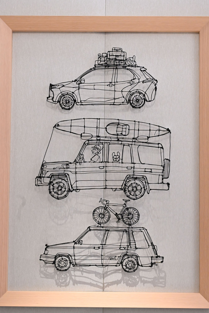 壁に飾られたワイヤーアート、上から「ヤリス」と「ランドクルーザー“70”」、そして「スプリンターカリブ」。