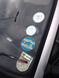 プロトンのフロントウィンドウに貼られたステッカー類。いずれも2004年の大学入構証やポロ・クラブのメンバー証が。