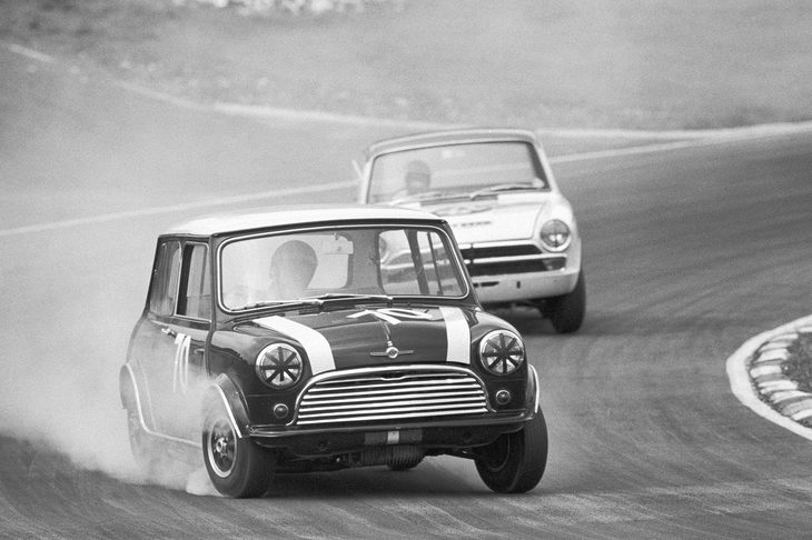 1966年にブランズハッチで行われたレースにて、「フォード・コーティナ」を従えて走るジョン・ローズの「ミニクーパーS」。ローズはタイヤスモークをまき散らす豪快な走りから“スモーキーローズ”というあだ名で親しまれた。