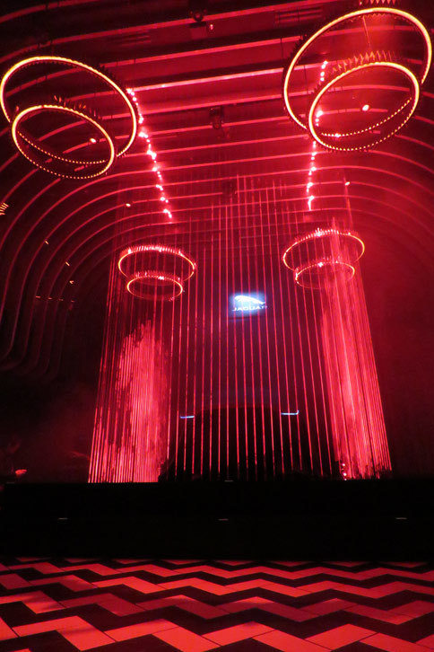 東京・六本木の会場にて、檻（おり）を思わせる赤いレーザーで飾られたステージ上の様子。