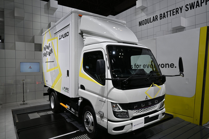 「三菱ふそうeキャンター」（バッテリー交換式モデル）と、バッテリー交換ステーション。
