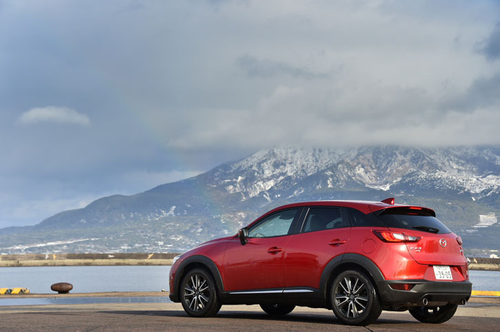 鹿児島で開催された、試乗会でのひとこま。雪化粧した桜島と、虹をバックにたたずむ「マツダCX-3 XDツーリング Lパッケージ」。