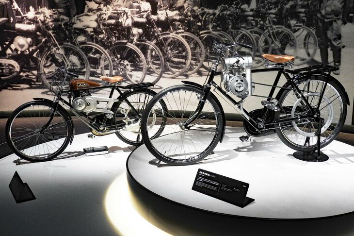 さっそく、展示と一緒にホンダの歴史をたどる。まずは今日のホンダの原点となった、無線機用エンジンを流用した自転車用補助エンジン（1946年）と、ホンダの名を冠した最初の製品である自転車用補助エンジン「A型」（1947年）。前者では、燃料タンクに湯たんぽや茶筒を使っていたという。