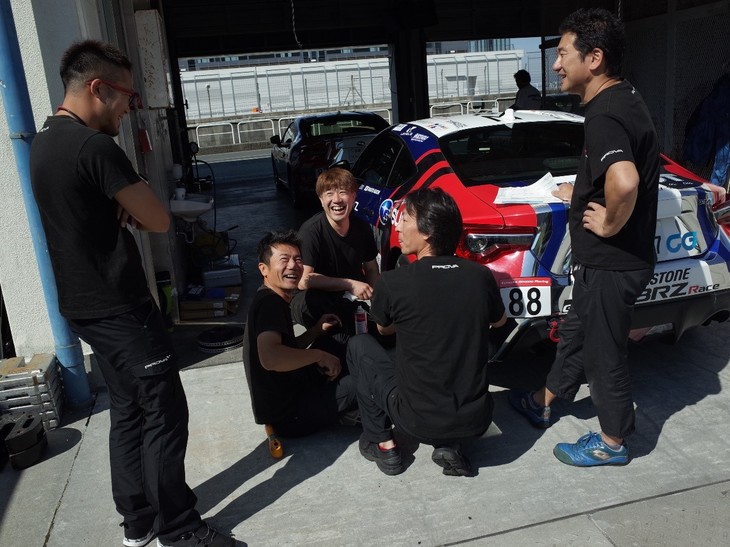 サーキットに到着してからは、ガレージを出て九州にあるオートポリスまで遠路旅をしてきた87号車、88号車、89号車の掃除、そして前回参加いただいたディーラーメカニックさんの“店舗名ステッカー”の貼り替えをしました。とっても楽しく作業しているのが、写真からも伝わってきます！