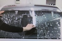 ダイノウインドシールドの施工シーン。柔軟性に富むポリウレタン製シールドを（界面活性剤を塗付した）フロントガラスに敷き、へらでならせば作業は完了。