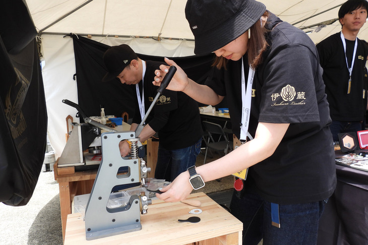 ブースではレザークラフト製作の実演も。伊の蔵・レザーでは500円玉がぴったりはまる、ワンコインキーホルダーを製作するワークショップも開催していたが、3枠24組はあっさり満員。受け付け終了となってしまっていた。
